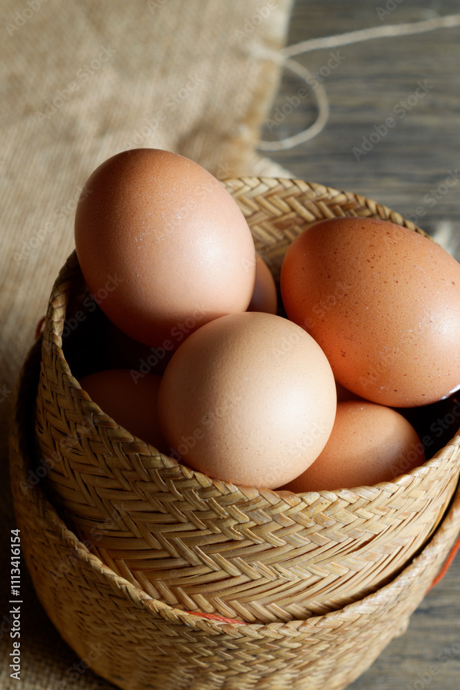 Fresh brown eggs nestled in a rustic wicker basket. The eggs have a warm, golden hue and appear to be organic. Fresh brown eggs nestled in a rustic wicker basket. The eggs have a warm, golden hue and appear to be organic.