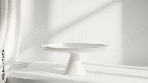 A white cake stand with a white cake on top of it