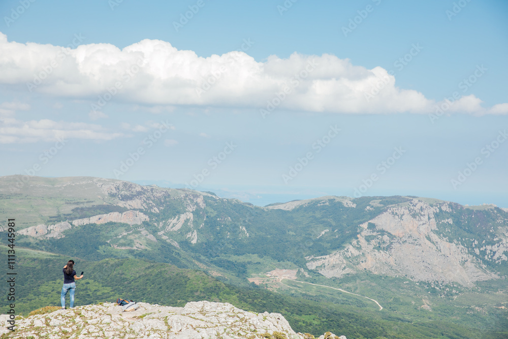 Female taking pictures of forest view from mountain top on hike Female taking pictures of forest view from mountain top on hike