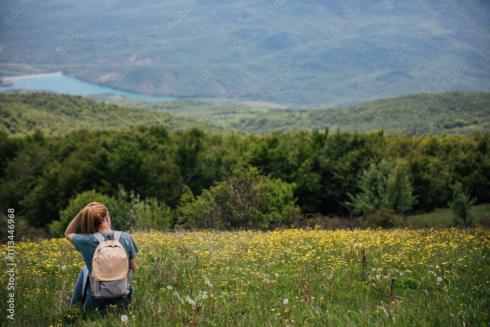 Female resting and looking at the forest from the top of the mountain on a hike Female resting and looking at the forest from the top of the mountain on a hike