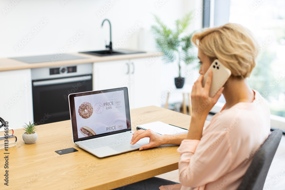 Caucasian woman ordering food online using laptop and phone at home. Concept of convenience and modern lifestyle with digital technology. Caucasian woman ordering food online using laptop and phone at home. Concept of convenience and modern lifestyle with digital technology.
