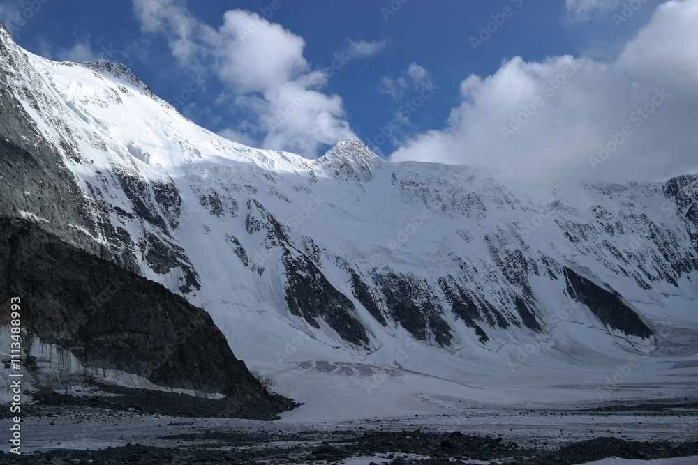 A stunning rock formation covered in snow, set against a clear blue sky with fluffy clouds in the background, creating a peaceful and breathtaking mountain landscape. A stunning rock formation covered in snow, set against a clear blue sky with fluffy clouds in the background, creating a peaceful and breathtaking mountain landscape.