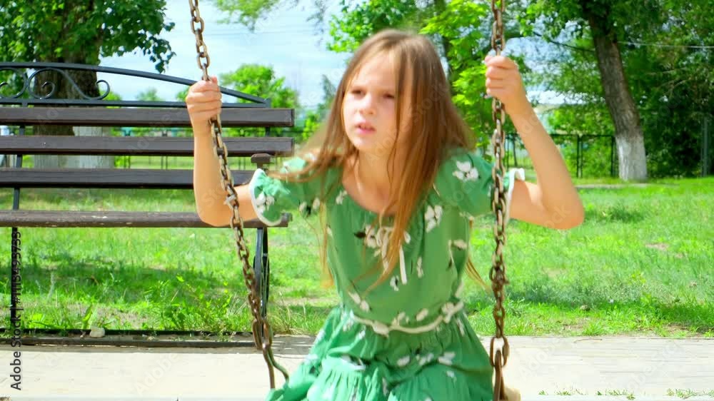 Slow motion school girl with long hair swinging outdoors on summer day. Cute girl have carefree fun on town children playground.