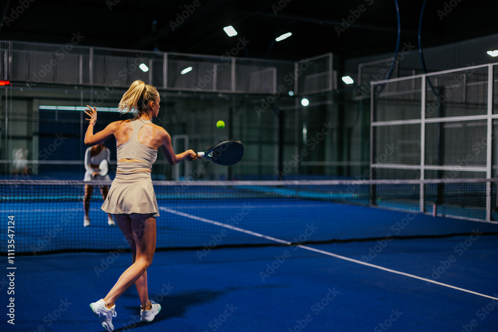Rear view of a female padel player playing padel Rear view of a female padel player playing padel