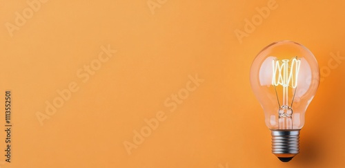 Bright vintage light bulb illuminated against a warm orange background