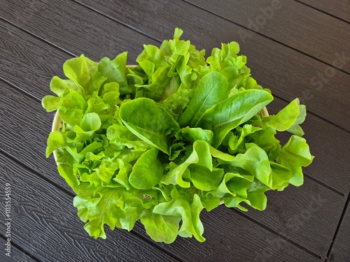 Fresh and organic green salad in the basket on the table. Famous clean vegetable side dish menu in healthy restaurant. 