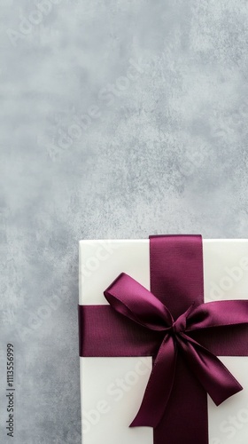 Beautifully wrapped gift box with burgundy ribbon on dark background ready fo...