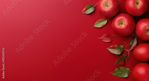 Fresh red apples placed on a vibrant red background with leaves, evoking a se...