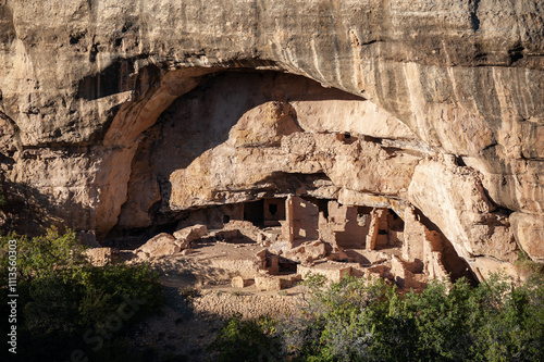 Ancient cliff dwelling ruins beneath a rocky overhang photo