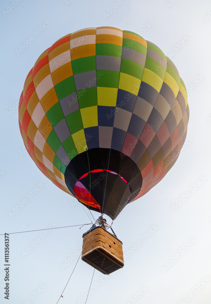 Fototapeta premium A colorful hot air balloon with a basket attached to it