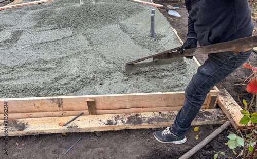 A man is laying concrete on a wooden platform photo