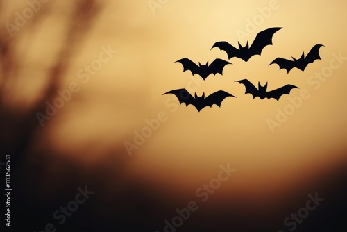 Bats flying against a warm sunset sky over a mysterious landscape