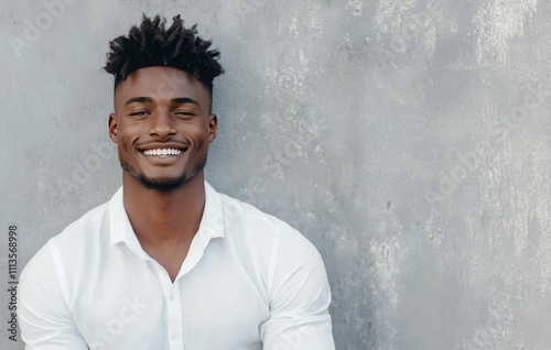 Smiling man in white t shirt poses against gray background showcasing confide...
