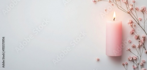 Delicate pink flowers and a lit candle create a calming atmosphere for relaxa...
