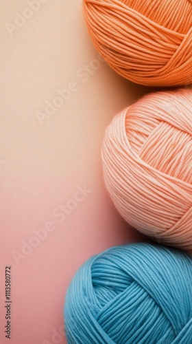 Display of colorful yarn balls in pastel shades arranged on a soft pink backg...