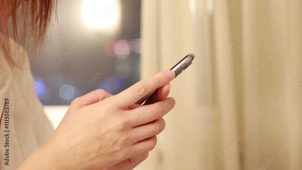 夜の明るい室内でスマートフォンを使用している女性 手 窓から見える夜景 イメージ 夜の明るい室内でスマートフォンを使用している女性 手 窓から見える夜景 イメージ