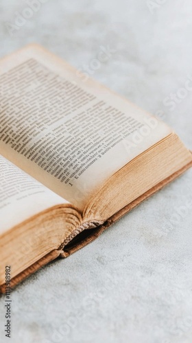 Old open book resting on a wooden surface with soft lighting and natural text...
