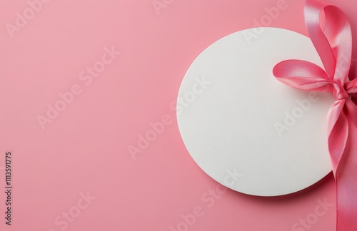 Plain white circular card placed on a pink background with decorative ribbon
