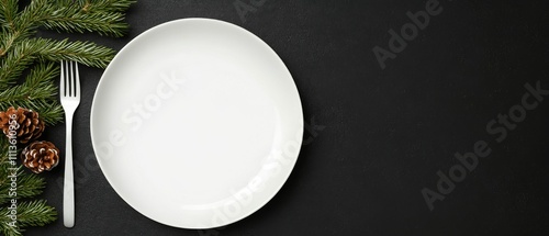 Empty plate on black table with pine branches and pine cones arranged artisti...