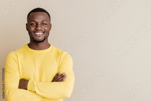 Smiling man in a yellow sweater stands confidently against a neutral background