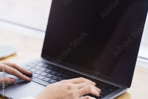 The image captures a woman's hands in detail, typing on a sleek laptop keyboard, set against a fuzzy office backdrop