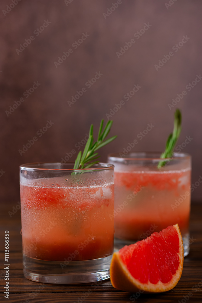 Grapefruit drink lemonade with peach, rosemary and ice on a wooden table. Healthy drink, sugar and alcohol free. Vertical orientation. Grapefruit drink lemonade with peach, rosemary and ice on a wooden table. Healthy drink, sugar and alcohol free. Vertical orientation.