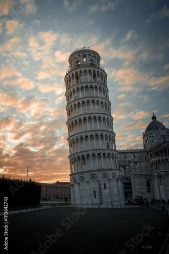 A breathtaking view of the Leaning Tower of Pisa during sunset. The iconic tower stands elegantly amidst a warm golden glow, with soft light highlighting its intricate architecture.