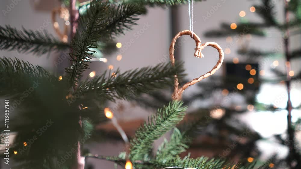 Heart shaped Christmas ornament from straw hanging from tree with bokeh lights
