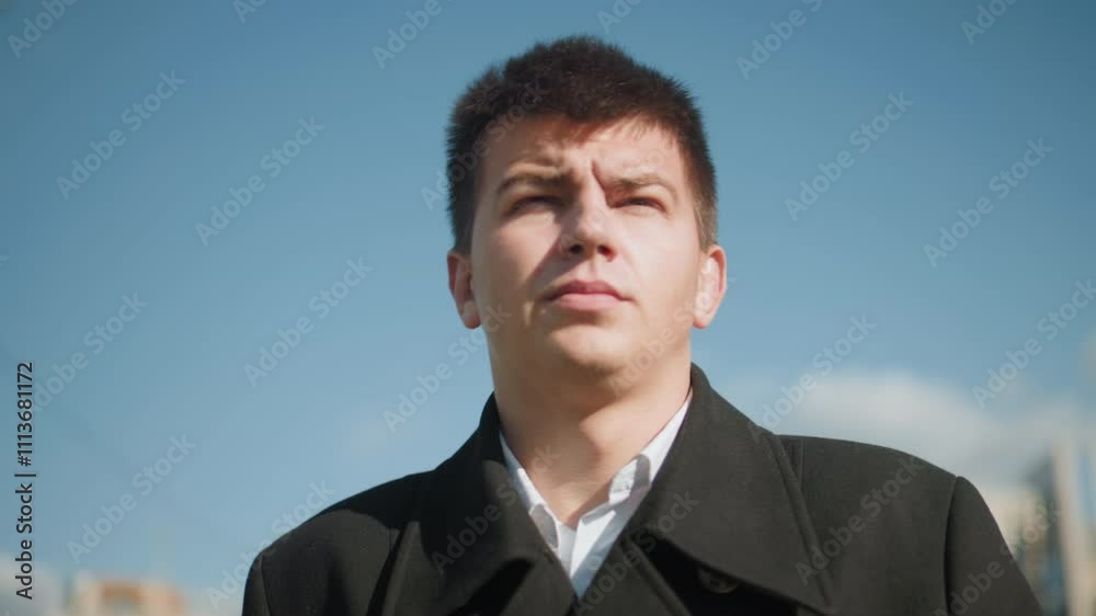 Close-up of investor walking confidently outdoors wearing elegant black coat, surrounded by modern urban buildings, blue sky, and blurred streetlights Close-up of investor walking confidently outdoors wearing elegant black coat, surrounded by modern urban buildings, blue sky, and blurred streetlights
