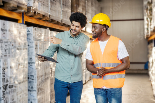 Fotografía Young diverse storage manager with tablet talking to his migrant black worker at warehouse