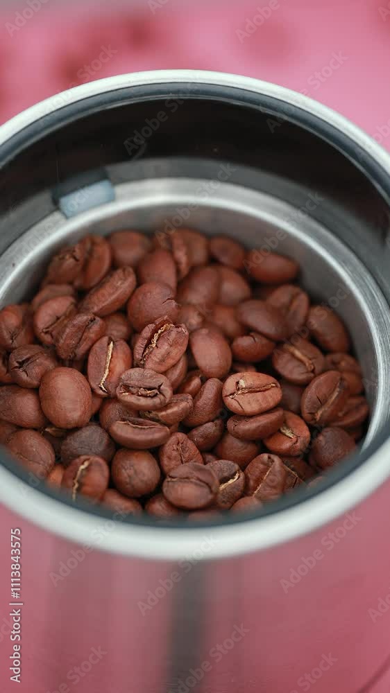 Top View Of Roasted Coffee Beans Inside A Stainless Steel Coffee Grinder On A Pink Background, Conveying Warmth And Energy. Perfect For Coffee Enthusiasts And Cafe-Themed Designs. Rotate.