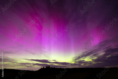 Silhouette of Dunstanburgh Castle with a spectacular Aurora above. Northumberland, England, UK. photo