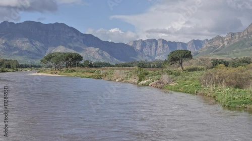 Breede River flows gently with mountains and green landscapes under a partly cloudy sky photo