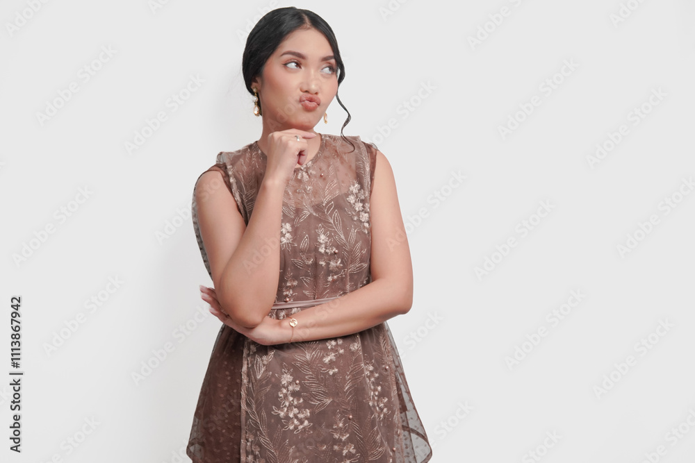 Thoughtful young Asian woman wearing brown brocade dress is thinking and imagining her thoughts. Thoughtful young Asian woman wearing brown brocade dress is thinking and imagining her thoughts.