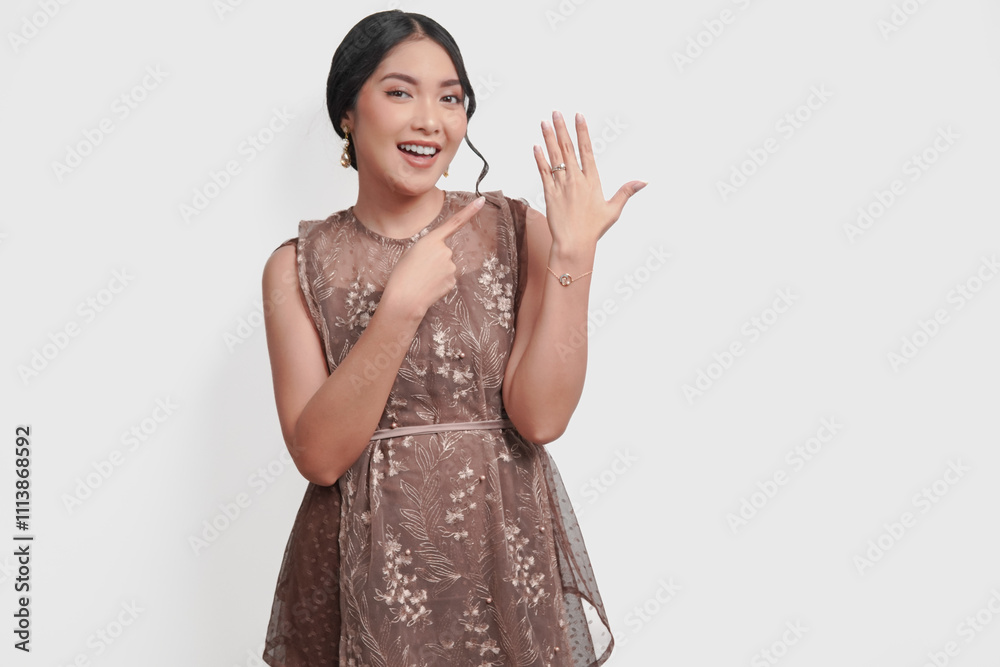 Beautiful young Asian woman in a brown brocade dress is presenting her engagement or wedding ring. Beautiful young Asian woman in a brown brocade dress is presenting her engagement or wedding ring.