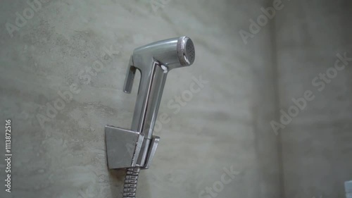 Handheld bidet in bathroom. Close up of chromium bidet shower in a toilet.