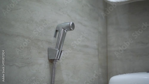 Handheld bidet in bathroom. Close up of chromium bidet shower in a toilet.