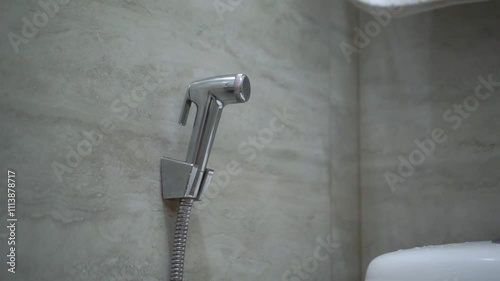 Handheld bidet in bathroom. Close up of chromium bidet shower in a toilet.