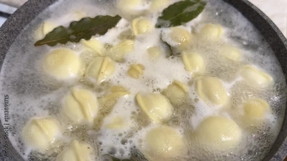 Dumplings in boiling water with seasonings and bay leaves in pan, slow motion. Close up photo of delicious preparation of simple meal in crock pot at home. Cooking meat dumplings in boiling water Dumplings in boiling water with seasonings and bay leaves in pan, slow motion. Close up photo of delicious preparation of simple meal in crock pot at home. Cooking meat dumplings in boiling water