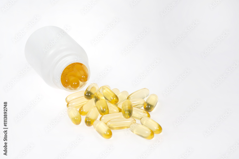 Omega 3 tablets spilling out of pill bottle isolated on white background. yellow pills close up. Fish oil capsules. Golden vitamin D3 Omega 3 tablets spilling out of pill bottle isolated on white background. yellow pills close up. Fish oil capsules. Golden vitamin D3