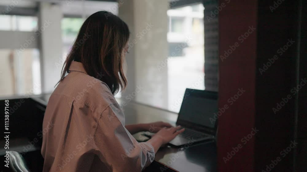 Determined young woman working on laptop in modern office