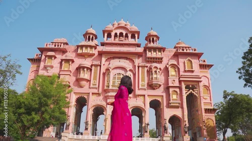 : Indian woman tourist wearing traditional saree and exploring architectural monuments in Jaipur, Rajasthan, India. Travel and tourism concept. Girl walking at Patrika Gate in Jaipur. photo