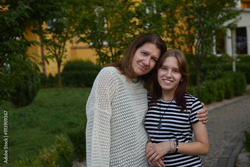 A mother and daughter share joyful moment together in a garden. The background features vibrant greenery, enhancing warm and intimate family scene. Ideal for family and relationship themes