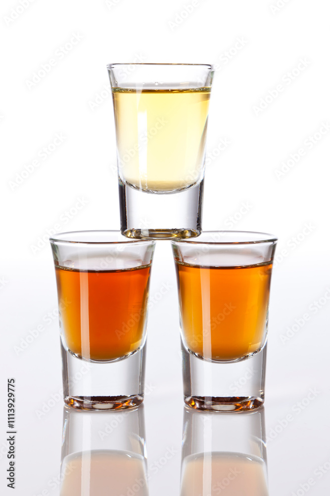 Stack of three shot glasses with different liquors, isolated Stack of three shot glasses with different liquors, isolated