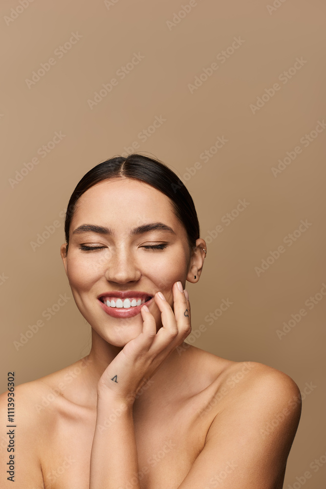 A young woman smiles brightly with closed eyes, radiating happiness against a simple backdrop. A young woman smiles brightly with closed eyes, radiating happiness against a simple backdrop.
