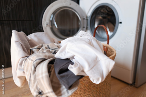 Photos A laundry basket with dirty clothes lies near a washing machine, focus on detergents and gels for removing tough stains