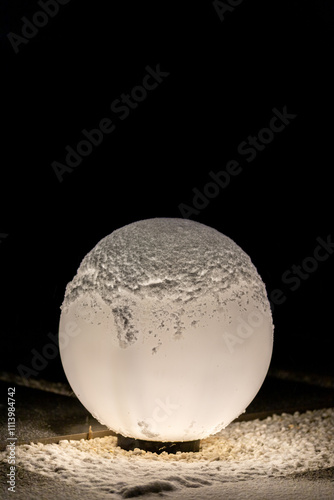 A globe lamp outside in the marble gravel covered with light snow