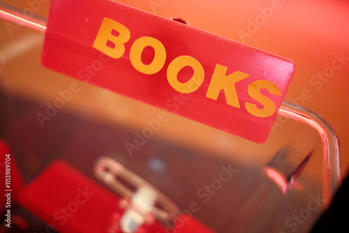 Close-up of a red BOOK' sign against a blurred background with a warm hue. photo