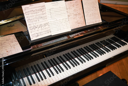 A grand piano with sheet music on the stand ready for a musician to play.