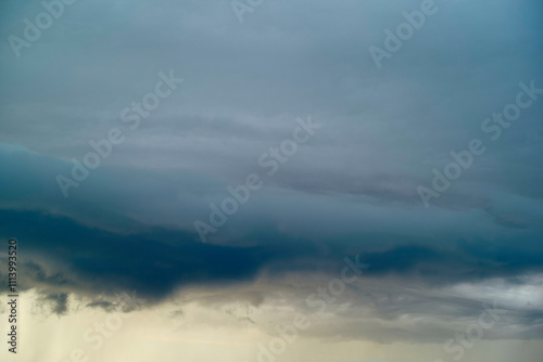 Dark storm clouds gather, indicating an approaching storm, with lighter clouds and a hint of sunset below, Norway